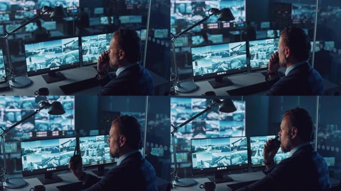 男警官在港口监控中心的一台带有监控闭路电视录像的计算机上工作，该中心在大屏幕上有多个摄像头。员工使用
