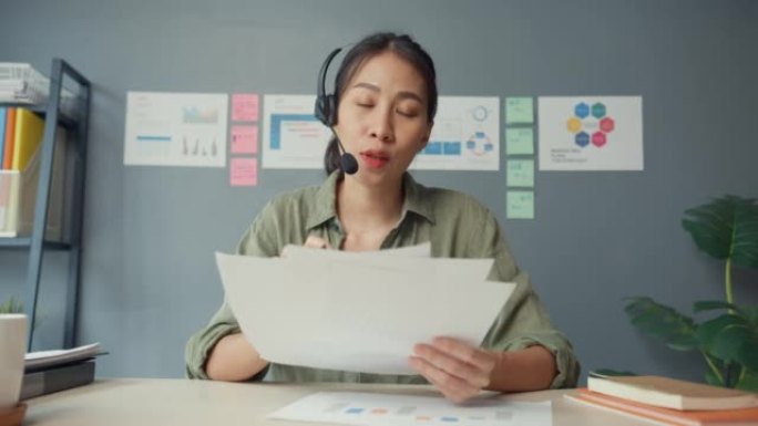 亚洲女商人在客厅在家工作时，使用笔记本电脑与同事讨论视频通话计划。