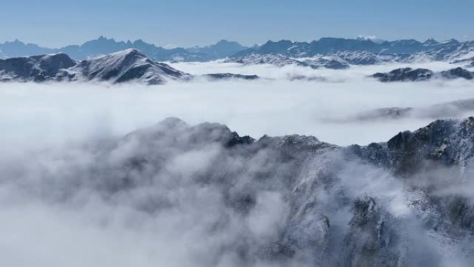 四川金山的雪山山脉令人惊叹的空中冬季景观，蓝天下有云雾