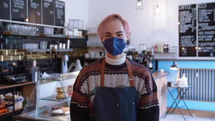 在咖啡馆工作的男子的肖像戴着口罩以避免冠状病毒