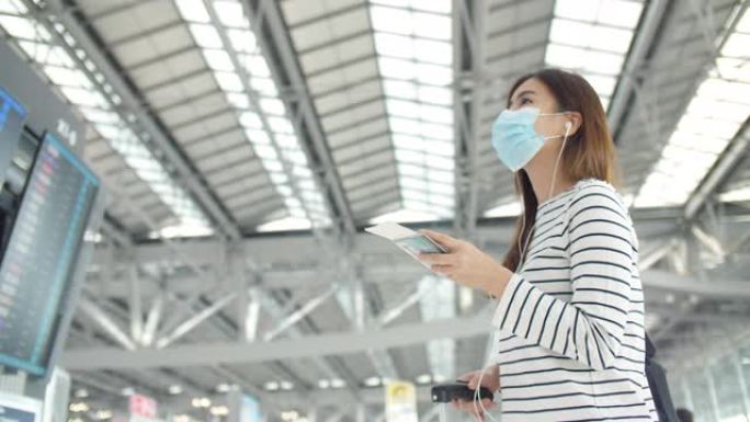 新型冠状病毒肺炎后旅行: 在机场航站楼戴着口罩检查航班的妇女