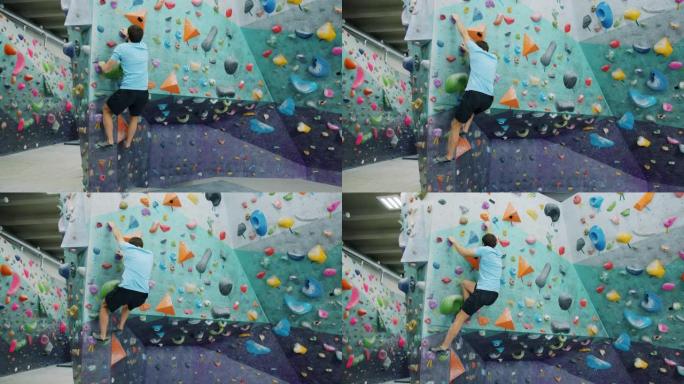 室内攀岩馆里的运动男训练拿着人造岩石爬上墙