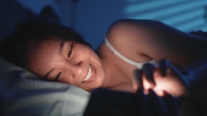 女人在晚上睡觉前在床上使用智能手机