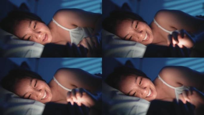 女人在晚上睡觉前在床上使用智能手机