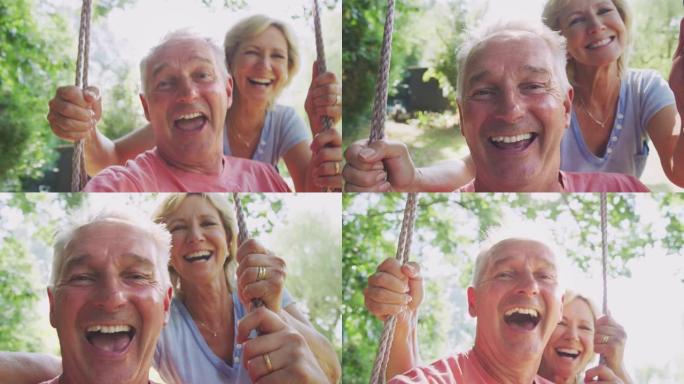 退休的高级夫妇的特写镜头与女人在花园秋千上推挤男人