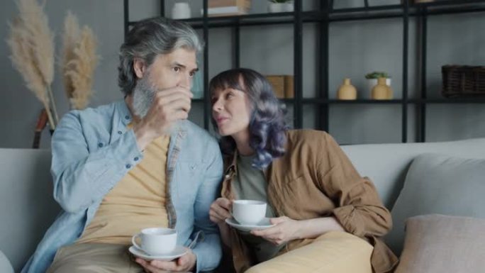 成熟男人和中年女人在家里的沙发上喝咖啡和聊天放松