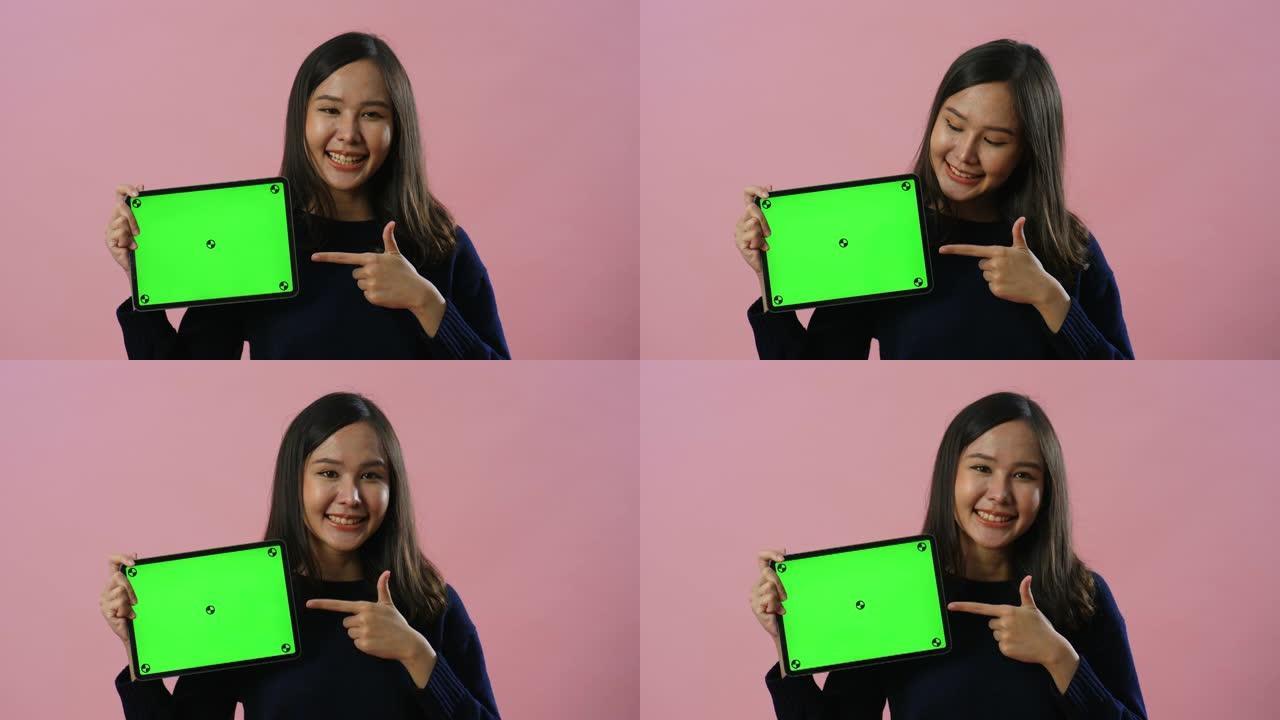 女人在绿屏上拿着数字平板电脑
