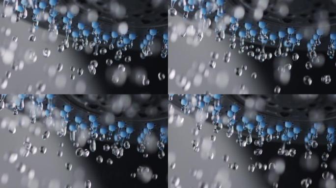 水滴从淋浴喷头上慢慢落下。淋浴水的慢动作镜头。微距镜头，黑色背景