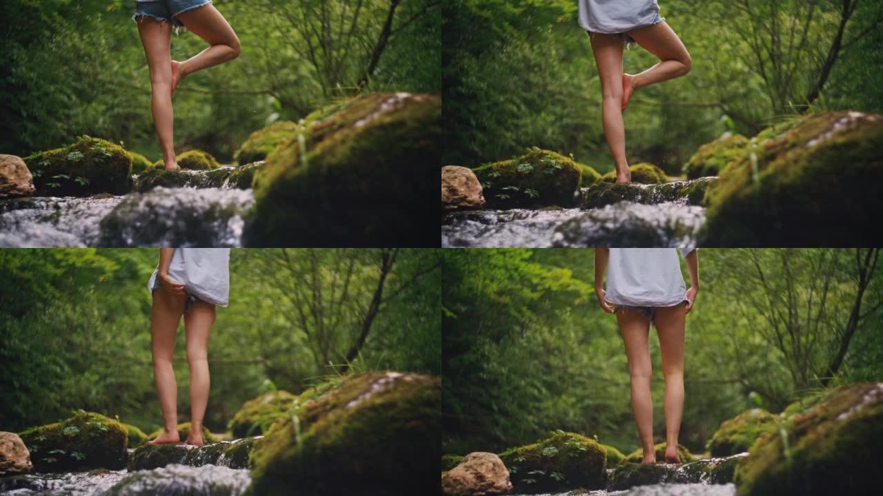 SLO MO年轻女子站在1英尺在溪流中的岩石上