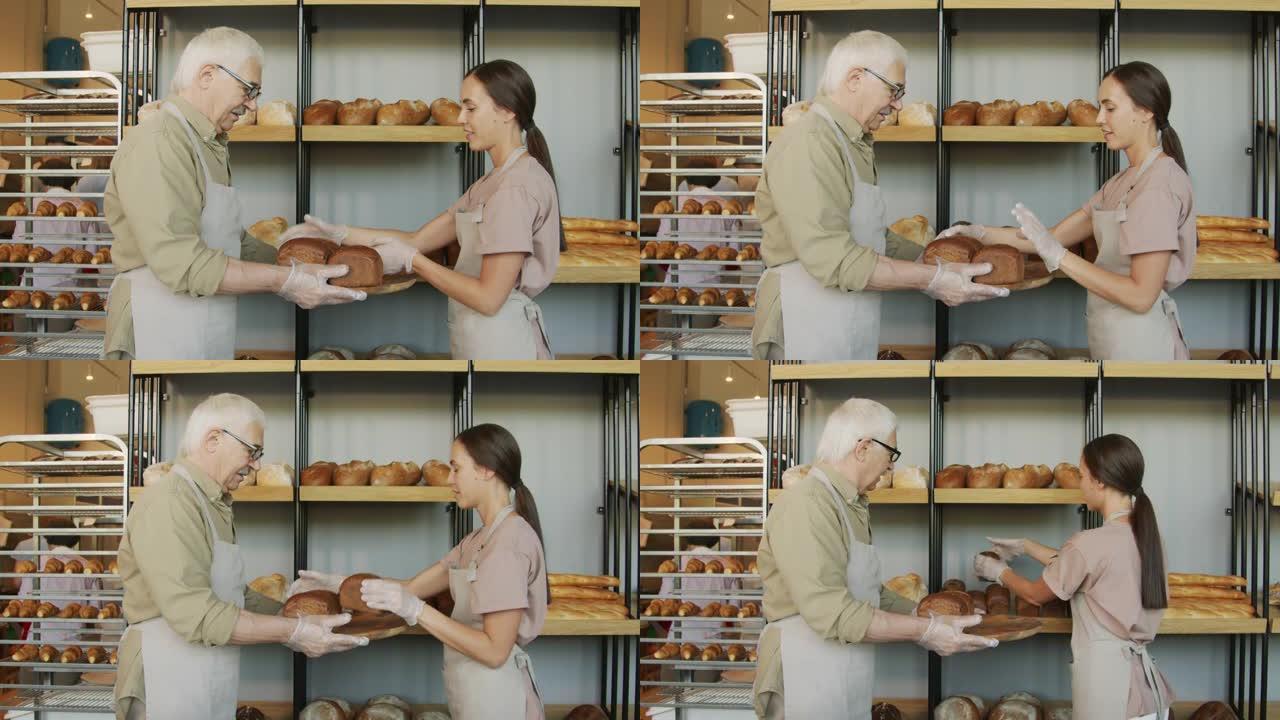 面包师和店主将面包放在面包店的架子上