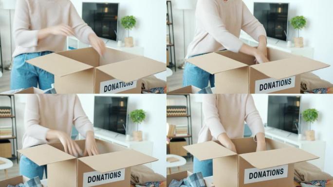 特写:在家里做慈善的女性手在装衣服的捐款箱