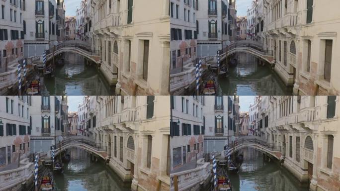 运河，桥梁和威尼斯的古老历史建筑一大早就没有人。摄像机沿着运河上的桥移动，万向节拍摄。意大利威尼斯