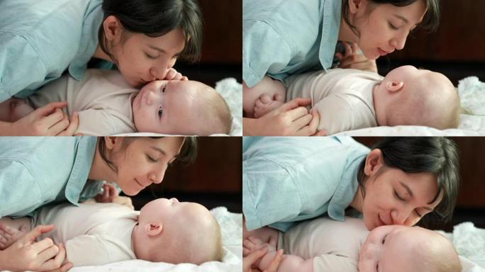 一位年轻的母亲深情地亲吻躺在床上的婴儿，传达出母亲对婴儿的爱。
