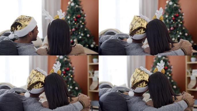 4k后方录像一对年轻夫妇坐在沙发上一起在家看圣诞节