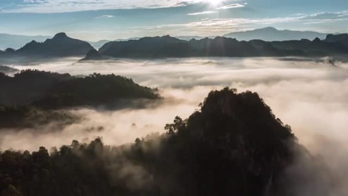 高山上方的空中超流雾和日出时穿过云层的阳光