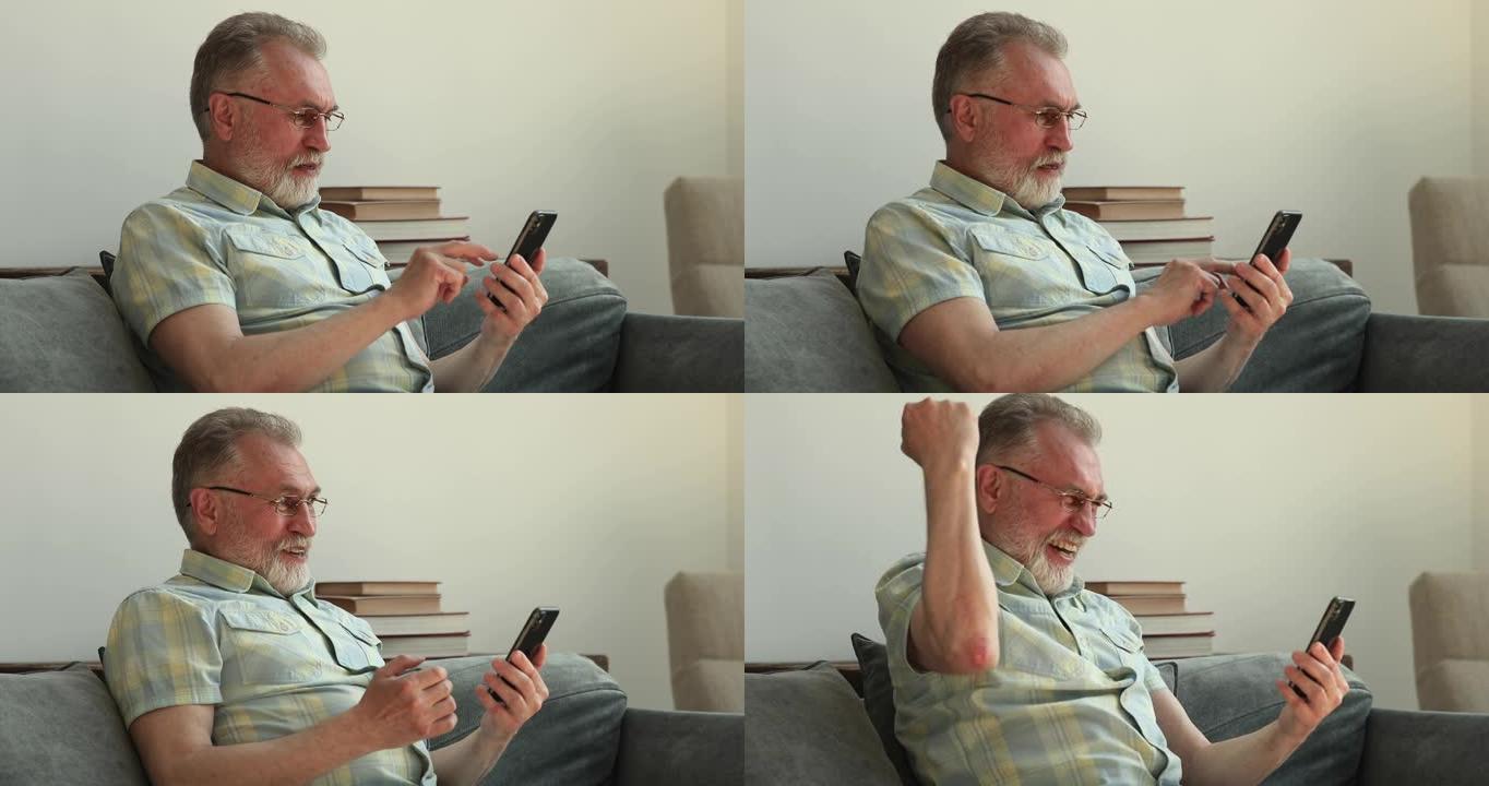 老年男性使用智能手机感到惊讶兴奋庆祝获奖