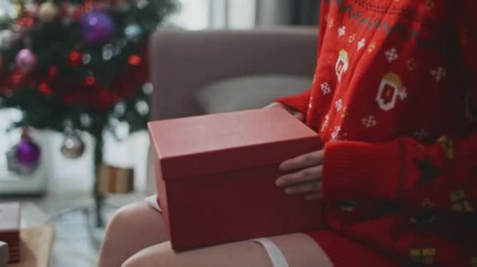 亚洲女性在家沙发上打开圣诞礼品盒