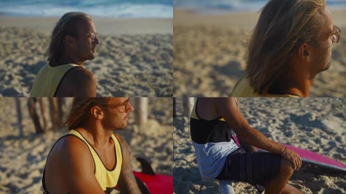 成年男子坐在沙滩上，看着大海，冲浪板躺在他旁边
