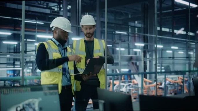 汽车工厂: 项目经理和汽车工程师戴着安全帽，说话，使用笔记本电脑。监控、控制、设备生产。自动机械臂装