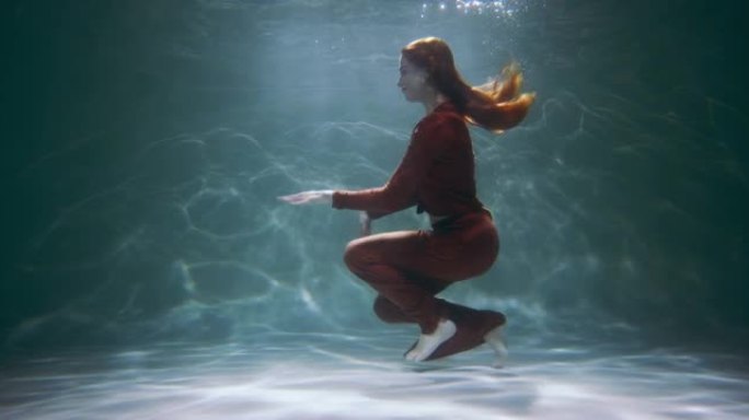 年轻快乐美丽活跃的红发女人玩得开心埃及舞蹈在水下慢动作。