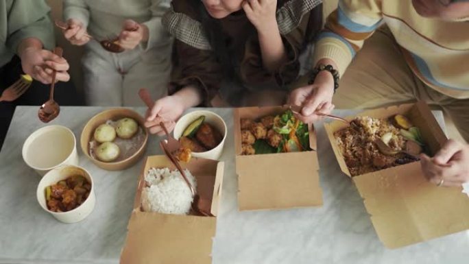 周末，亚洲华人年轻家庭的双手在客厅的电视前享受外卖食物