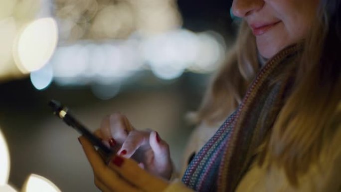 DS女人在节日灯光照亮的城市中使用智能手机