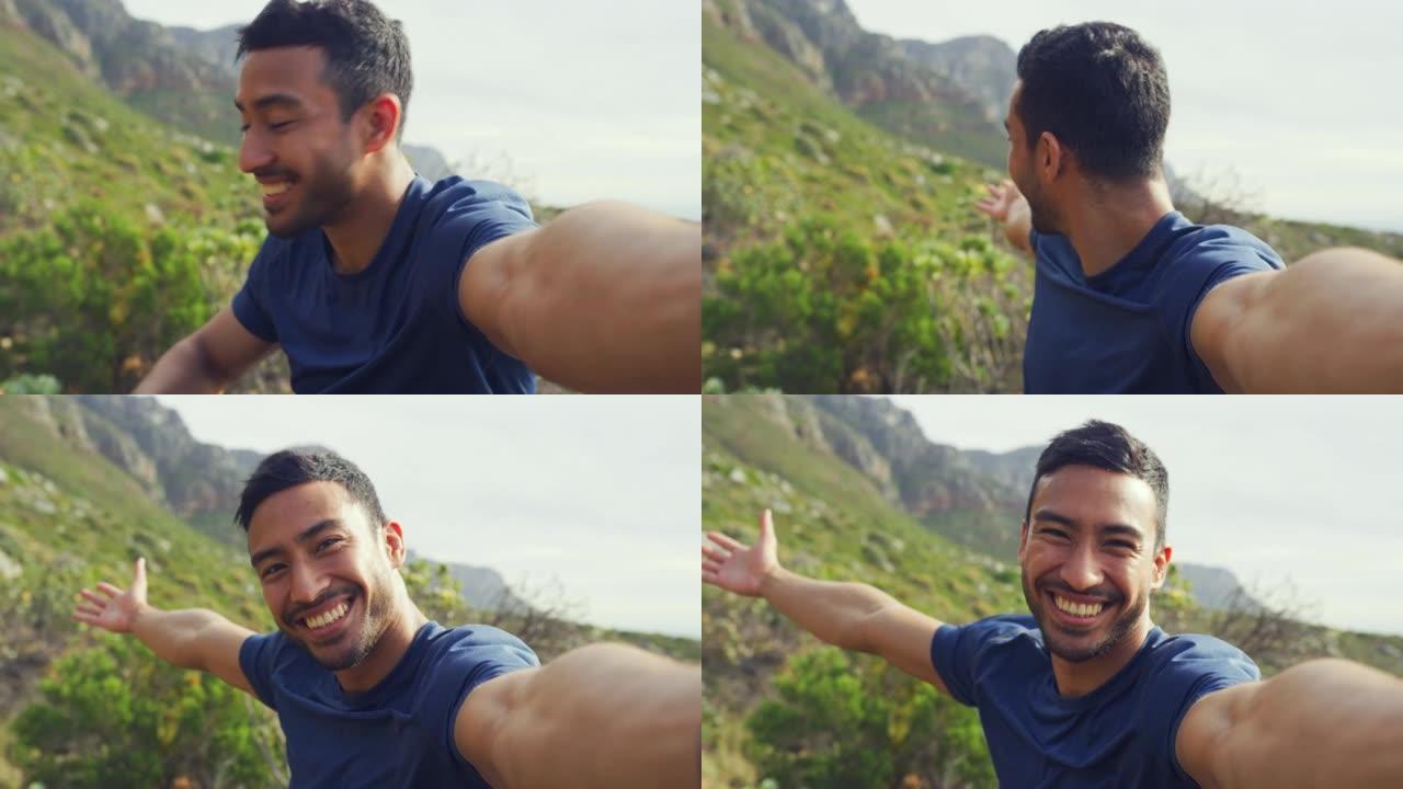 一个快乐男人徒步旅行的肖像，一边自拍一边指着风景，一边打视频。面对一名年轻的拉丁裔游客，在大自然的跋