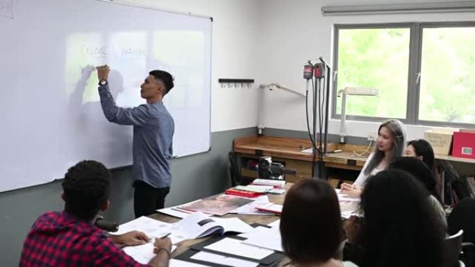 亚洲马来男讲师在教室里用白板向学生讲授珠宝设计课