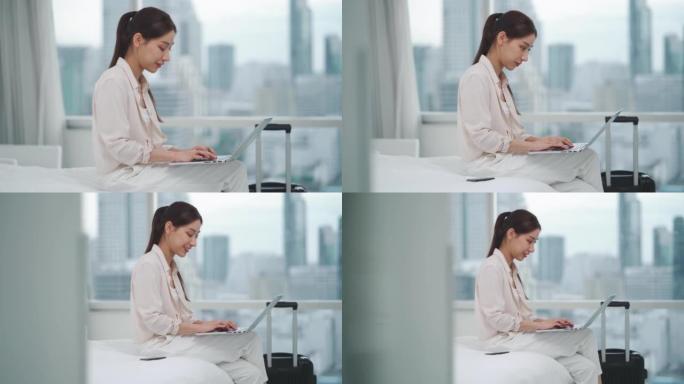 亚洲女商人在进入房间时使用技术平板电脑在床上工作