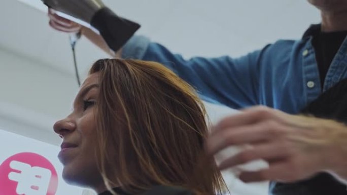 慢动作发型师在美容院为女性顾客干头发