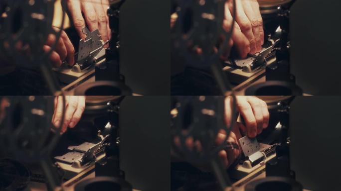 男人的手的特写镜头，将8毫米的电影填充到一个特殊的剪辑机中。