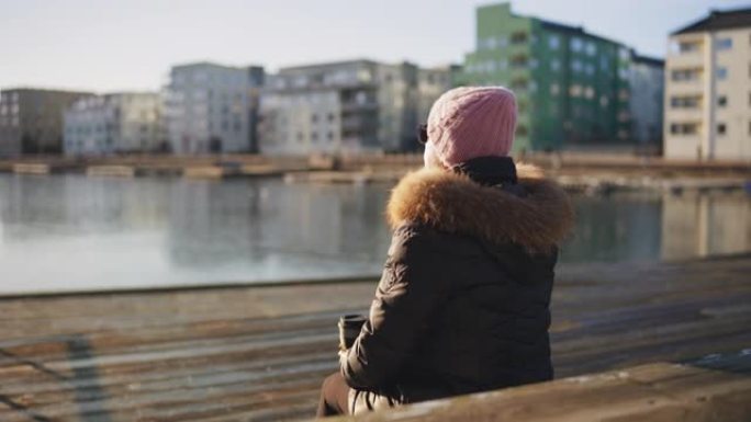 在冬日的阳光下享受热茶的高级女性