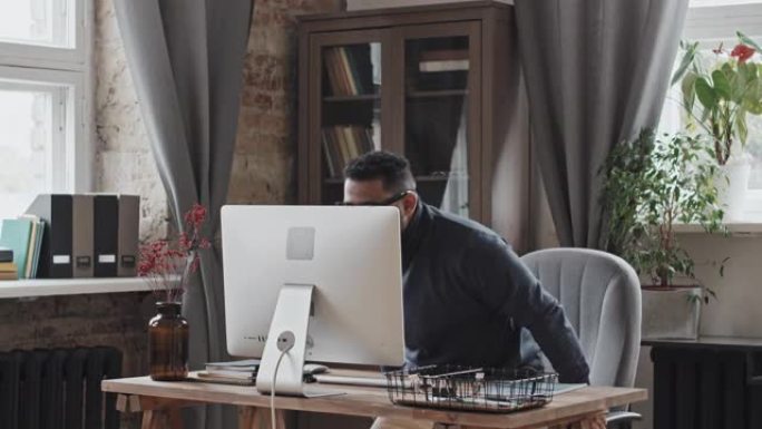 中东男子坐在办公桌前，在计算机上进行视频通话