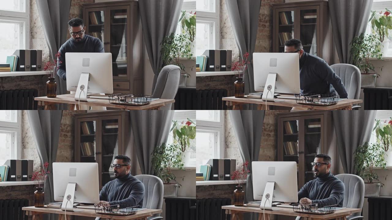 中东男子坐在办公桌前，在计算机上进行视频通话