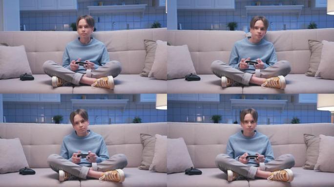 年轻英俊的游戏男孩坐在沙发上，在数字控制台上玩视频游戏的肖像。兴奋的玩家控制视频游戏操纵杆。一个人专