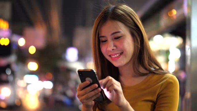 在城市之夜使用智能手机的女人