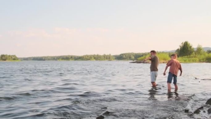 男子和儿子扔石头站在湖里