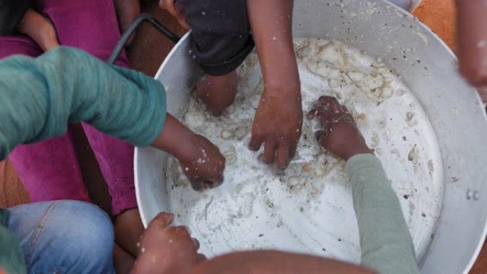 非洲的贫困。一小群饥饿的非洲黑人儿童从公共炊具的底部刮食物