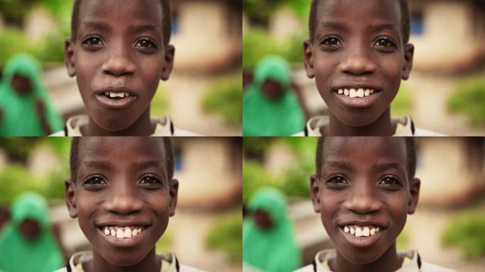 一个害羞的真实的非洲男孩的特写肖像，在镜头前摆姿势和微笑，背景是一个模糊的乡村。对未来充满希望的黑人