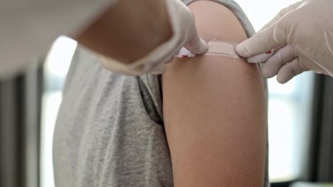 男药师接种疫苗后将绷带放在女性手臂上特写