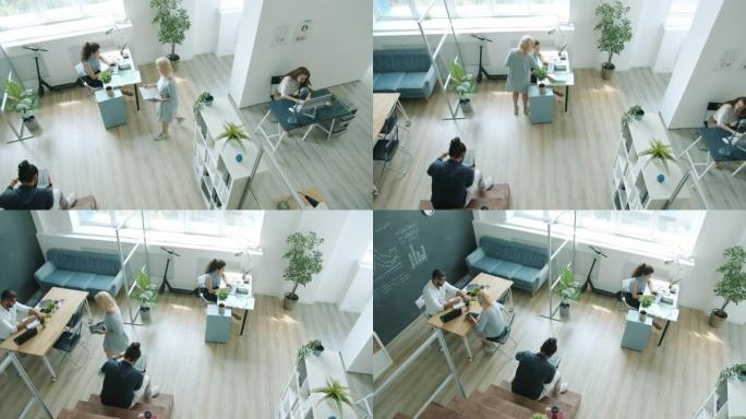 员工在办公室工作的男性和女性使用计算机说话走路的高角度视图