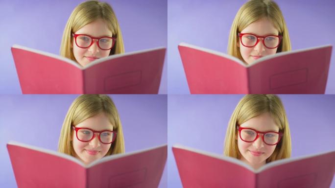 戴眼镜的女孩在紫色背景下学习学校练习册的工作室镜头 -- 慢动作镜头