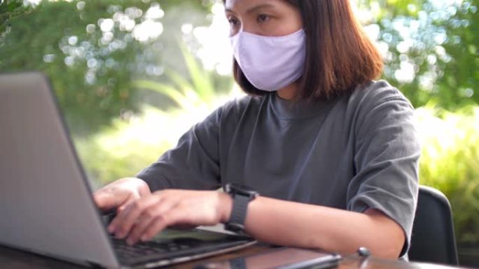 冠状病毒新型冠状病毒肺炎传播期间戴着口罩在家工作的年轻女子