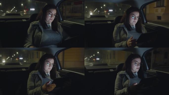 女人晚上在汽车上打电话和使用数字平板电脑