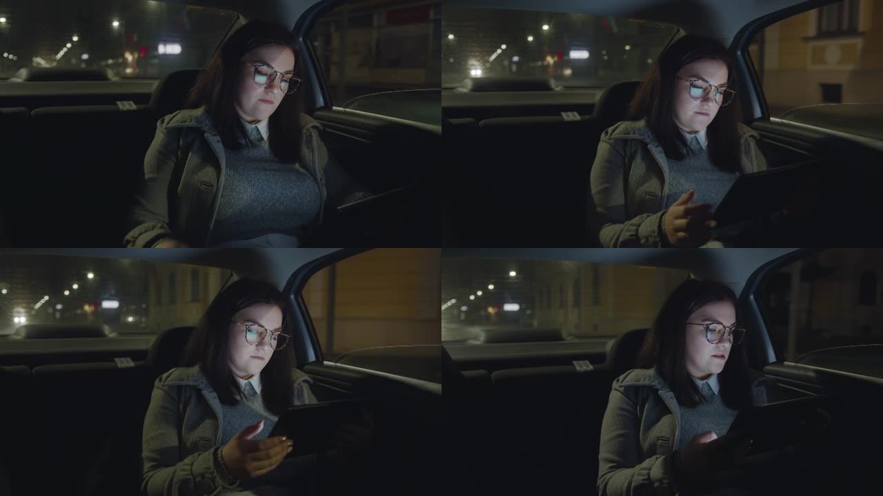 女人晚上在汽车上打电话和使用数字平板电脑