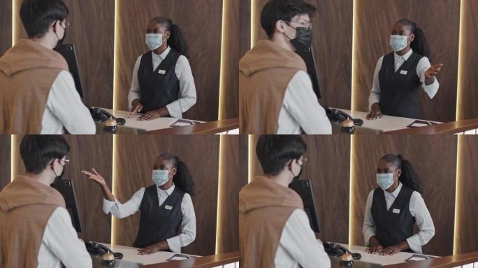 接待员戴着口罩与酒店客人一起工作