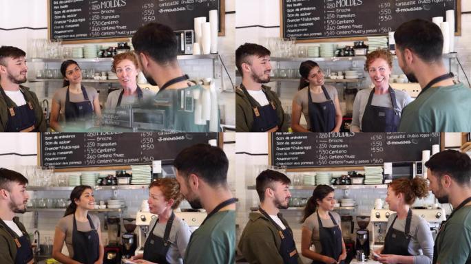 一家咖啡店的开朗企业主在营业前与她的团队交谈，所有人都站在柜台后面