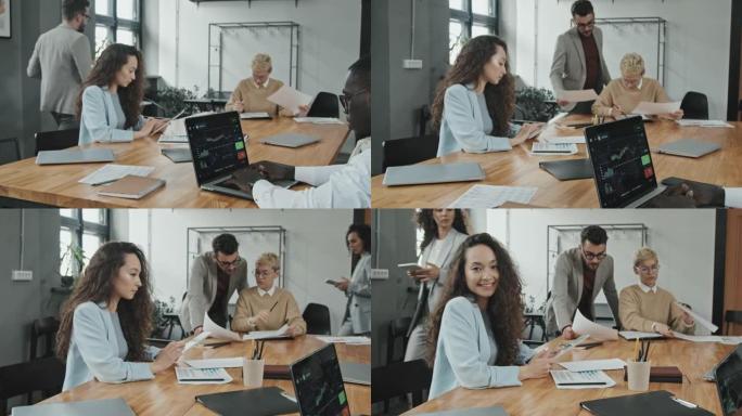 微笑的女商人与同事一起工作并摆姿势拍照