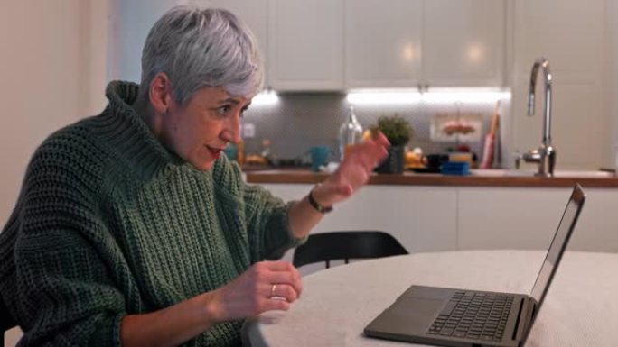 高级妇女在家里用笔记本电脑进行视频通话