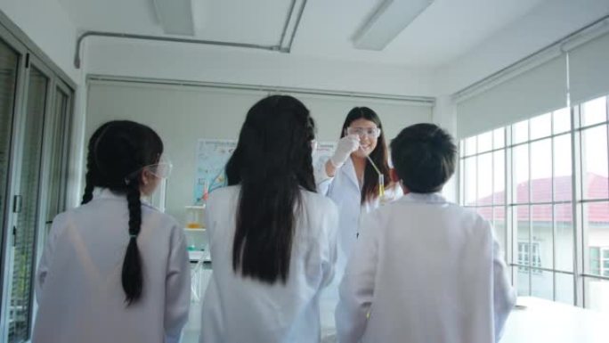科学家老师在学校的实验室课上与小学生讲话。